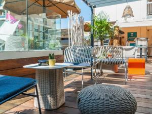Un patio con sillas y mesas y una sombrilla. en Mercure Toulouse Centre Saint-Georges, en Toulouse