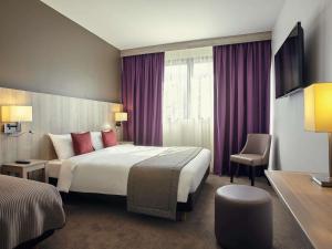 a hotel room with a large bed and purple curtains at Mercure Versailles Paris Ouest in Versailles