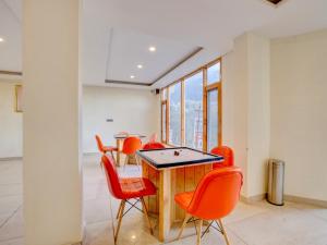 a dining room with orange chairs and a table at Omavya luxury hotel & cottage -with bonfire , apple orchid ,mountain view , parking in Vashisht