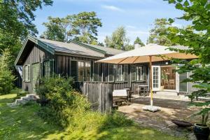 una casa de madera con una sombrilla en el patio en Summer House With Large Nature Plot In Rørvig, en Rørvig