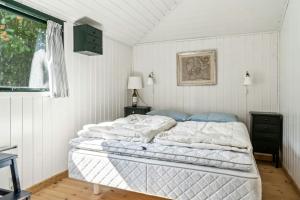 Un dormitorio con una cama con sábanas blancas y una ventana. en Summer House With Large Nature Plot In Rørvig, en Rørvig