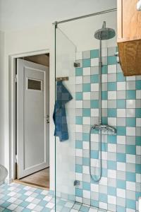 Un baño con ducha con azulejos azules y blancos. en Summer House With Large Nature Plot In Rørvig, en Rørvig