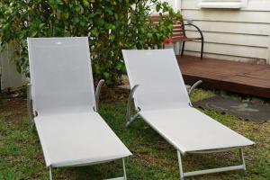 Twee witte stoelen staan in het gras naast een bankje. bij Dodo Coconut lagon Ermitage in Saint-Gilles-les-Bains
