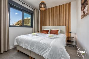 een slaapkamer met een bed met witte lakens en een raam bij VIVI Homes - Bonita del Sol Beach, Pool, Garden, GYM & SPA in La Cala de Mijas