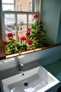 a sink in a bathroom with a window with red flowers at High Street Hostel - Over 18s Only, Backpackers Atmosphere in Edinburgh