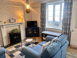 een woonkamer met een blauwe bank en een open haard bij Seaview Terrace - Beer in Beer