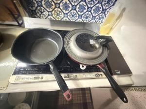 two pots and pans sitting on top of a stove at sakuraの家 in Tokyo