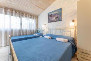 een slaapkamer met twee blauwe bedden en een raam bij Villa Messapia in Torre dell'Orso +20 foto's