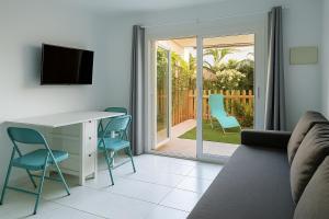 ein Wohnzimmer mit einem Sofa, einem Schreibtisch und Stühlen in der Unterkunft Maspalomas Green Oasis 1404 in Maspalomas