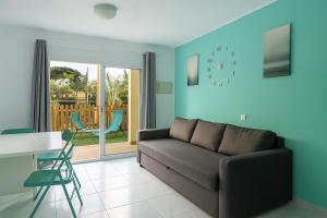 ein Wohnzimmer mit Sofa, Tisch und Stühlen in der Unterkunft Maspalomas Green Oasis 1404 in Maspalomas