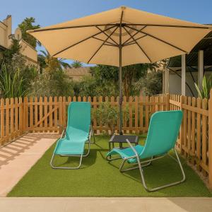 zwei Stühle und ein Regenschirm auf einem Hof in der Unterkunft Maspalomas Green Oasis 1404 in Maspalomas