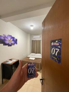 a person opening a door to a room at Pousada das Flores in Aparecida