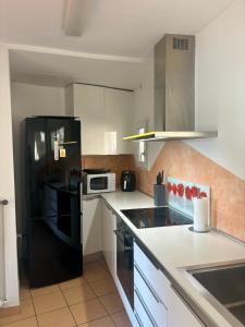 une cuisine avec un réfrigérateur noir et des armoires blanches dans l'établissement Rovio Villa lake View & Relax, Lago di Lugano 4guests, à Lugano