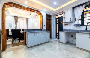 a kitchen with white cabinets and a dining room at Emerald Greens 3-Bedroom House in Thika +19 photos