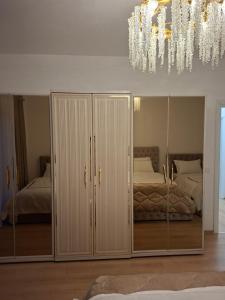 una camera da letto con armadi a specchio e un lampadario di Heart Apartment Tirana a Tirana Altre 2 foto