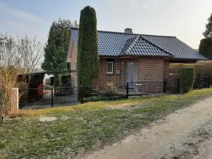 ein Backsteinhaus mit einem Zaun davor in der Unterkunft Ferienhaus direkt am See in Blankensee
