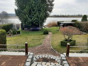 Ein gemauerter Gehweg führt zu einem Garten mit See in der Unterkunft Ferienhaus direkt am See in Blankensee