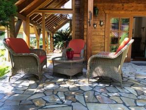 een terras met drie stoelen en een tafel op een stenen terras bij Blockhaus am Waldrand in Brieselang