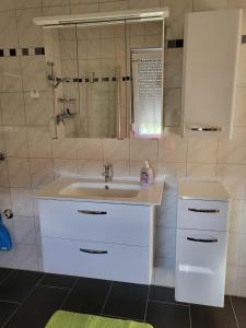 a white bathroom with a sink and a mirror at Ferienwohnung Zühlensee in Wesenberg +4 photos