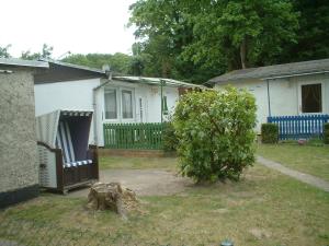 a house with a fence and a tree in a yard at Ferienbungalow Fleesensee in Malchow