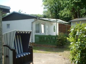 a chair sitting in a yard next to a house at Ferienbungalow Fleesensee in Malchow +5 photos
