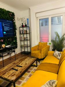 a living room with yellow furniture and a tv at Little Lodge Hôtel in Brest
