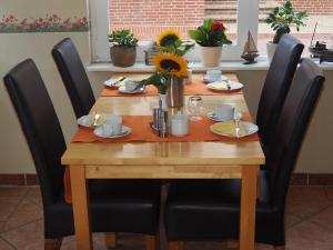 a wooden table with black chairs around it with flowers on it at Pension Lüttje Meermaid in Borkum
