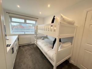 een wit stapelbed in een kamer met een raam bij Dalton House - Private Parking in Blackpool