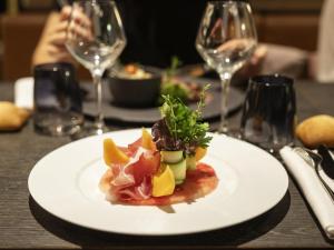 une assiette de nourriture sur une table avec des verres à vin dans l'établissement Novotel Strasbourg Centre Halles, à Strasbourg
