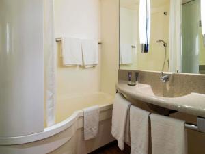 Un baño con bañera, lavabo y espejo. en Novotel Metz Amnéville, en Maizières-lès-Metz