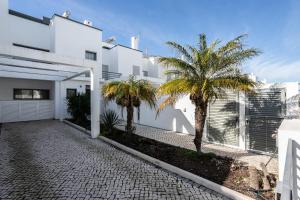 ein weißes Haus mit Palmen davor in der Unterkunft Villa Conchas by Algarvemanta in Manta Rota