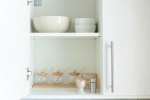ein weißer Schrank mit Schüsseln und Tellern darin in der Unterkunft Parking gratuit I Duplex gare 2min I Paris direct15min in Versailles