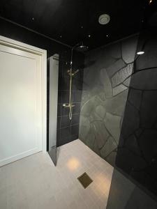 a bathroom with a shower with a stone wall at Villa Aurora Noir in Rovaniemi +23 photos