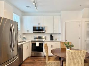 a kitchen with a table and a stainless steel refrigerator at New 1B1B Condo in Old Fourth Ward 542Blvd207 in Atlanta +5 photos