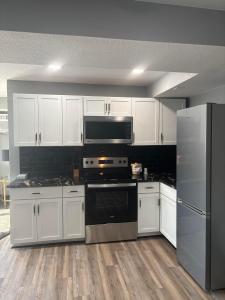 a kitchen with white cabinets and a stove and refrigerator at Plymouth Suites in Plymouth