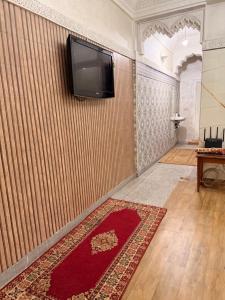 a room with a tv on a wall with a red rug at Julie Airport Boarding Apartment in Marrakesh