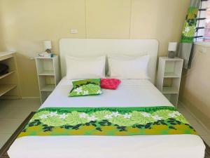 a bed with two colorful pillows on it at Pokata Studio Unit 2 in Rarotonga