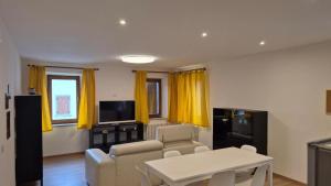 a living room with yellow curtains and a tv at Silvia's Home in Calalzo +5 photos