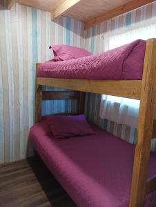 2 stapelbedden in een kamer met paarse lakens bij Cabañas Sandra Bucalemu Alto in Bucalemu