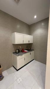 een keuken met witte kasten en een aanrechtblad bij شقة بصالة وغرفه نوم in Hafr Al Baten