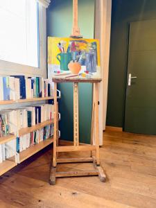 a table with a painting on it next to a book shelf at Urban Oasis - Duplex Design, Piscine privée in Perpignan