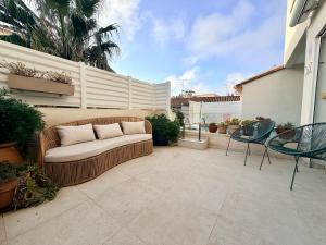 a couch on a patio with chairs and a fence at Urban Oasis - Duplex Design, Piscine privée in Perpignan