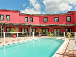 een rood gebouw met een zwembad voor een gebouw bij ibis Macon Sud Crêches in Crêches-sur-Saône
