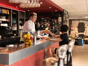 a man and a woman standing at a bar at Hotel ibis Narbonne in Narbonne