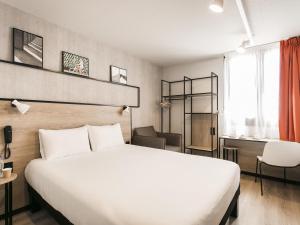 a hotel room with a white bed and a desk at ibis Avignon Sud in Avignon