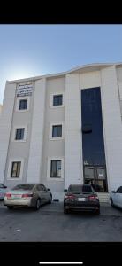 twee auto's geparkeerd voor een gebouw bij شقة بصالة وغرفه نوم in Hafr Al Baten