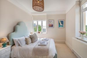 a bedroom with a bed with a blue headboard and windows at 4 Bed in Instow oc-clevv in Instow