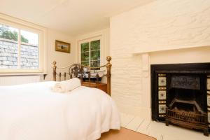 a white bedroom with a bed and a fireplace at Ladye Park in Liskeard