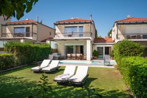 a house with a yard with lounge chairs and a pool at Sunny Exclusive Ena in Hanioti