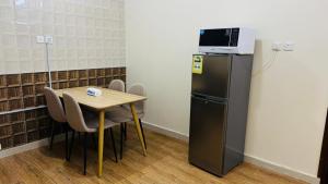 a kitchen with a table and a microwave on top of a refrigerator at شقق ترانيم السراة للشقق المخدومة - اقتصادي in Baljurashi